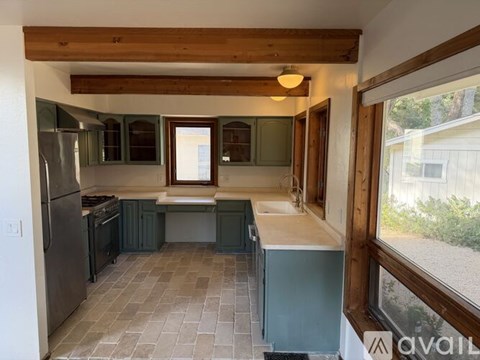 A kitchen with green cabinets and a tiled floor.