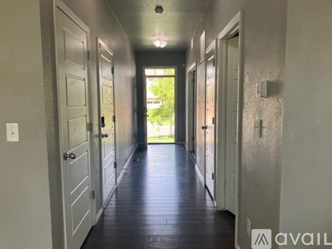 A long hallway with doors on both sides and a window in the distance.