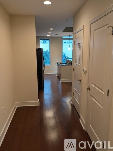 A hallway with a black door on the left and white doors on the right.