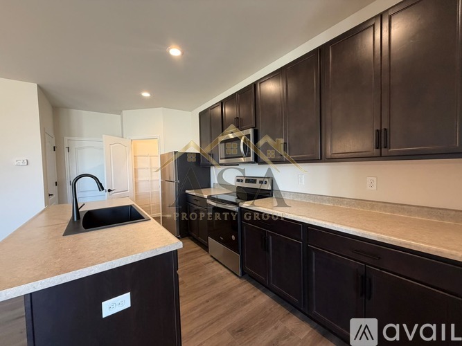 A kitchen with dark brown cabinets and a countertop with a sink.