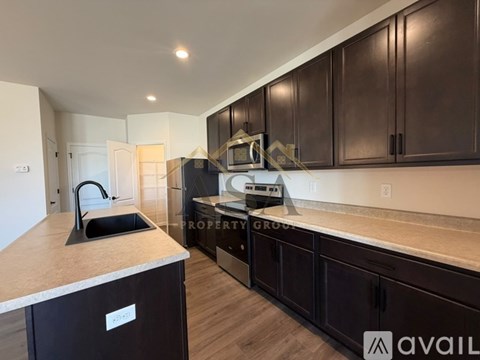 A kitchen with dark brown cabinets and a countertop with a sink.