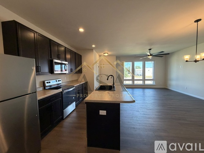 A modern kitchen with black cabinets and a stainless steel refrigerator.