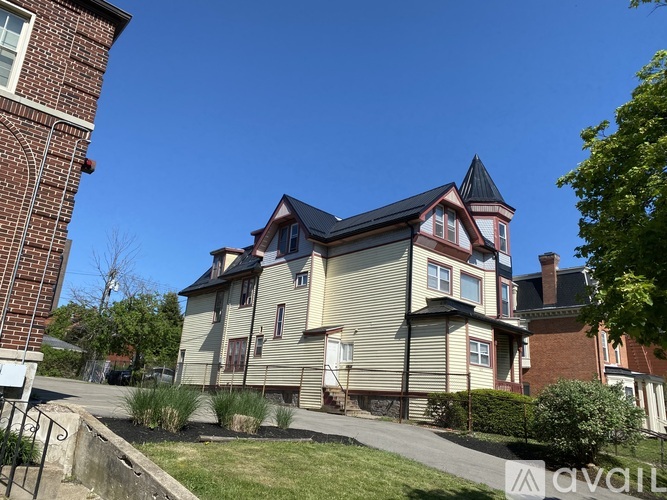 A house with a red brick building to the left and a house with a brown roof and a tower to the right.