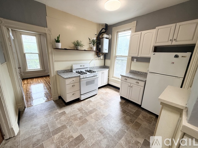A kitchen with white appliances and a tiled floor.