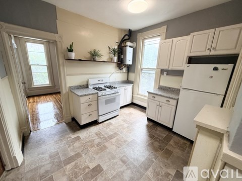 A kitchen with white appliances and a tiled floor.