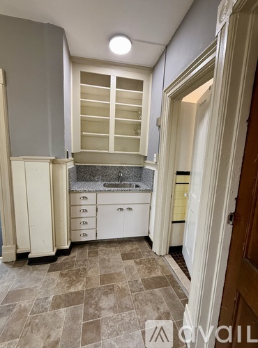 A kitchen with a tile floor and white cabinets.