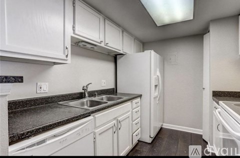 A kitchen with white cabinets and a black countertop.