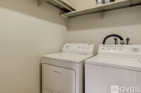 Two white front loading washing machines in a small laundry room.