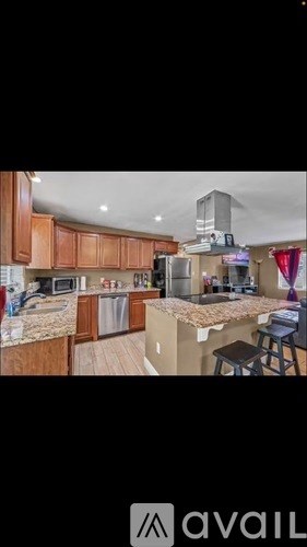 A kitchen with wooden cabinets and a central island with a bar stool.