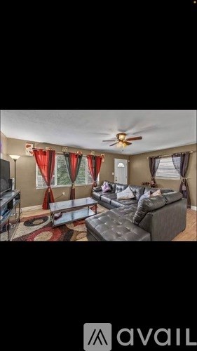 A living room with a grey couch and red curtains.