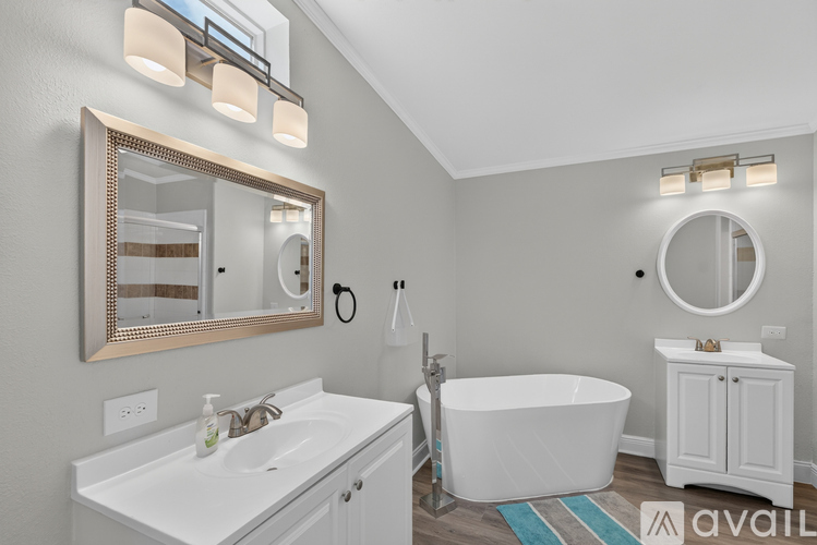 A bathroom with a white tub, sink, and mirror.