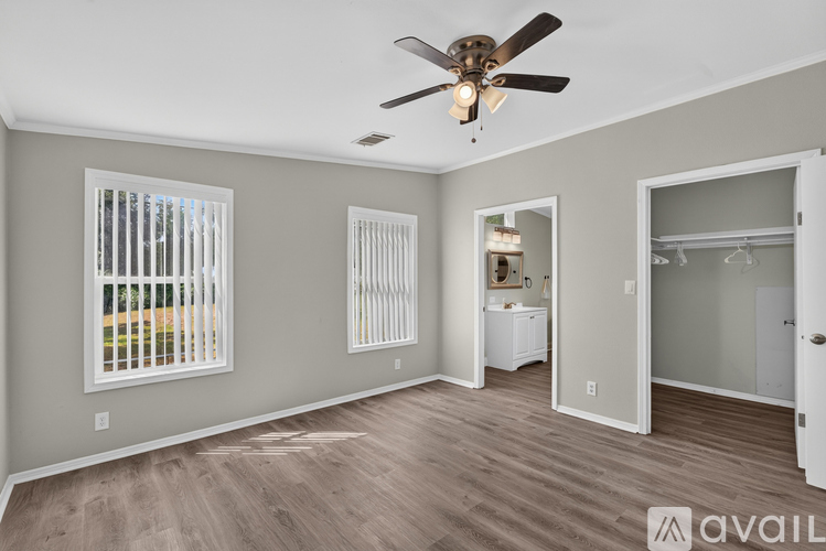 A spacious room with a ceiling fan and wooden flooring.