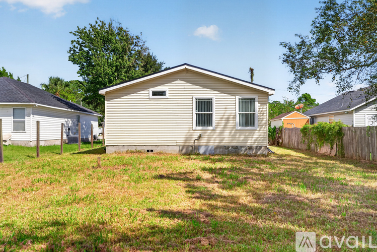 A house with a brown roof and a grey siding is surrounded by a grassy area.