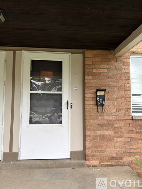 A white door with a glass window and a mailbox on the brick wall.