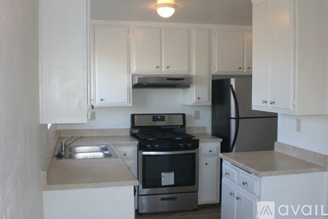 A kitchen with white cabinets and a stainless steel refrigerator.