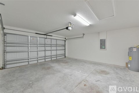 A spacious garage with a closed metal door and a concrete floor.