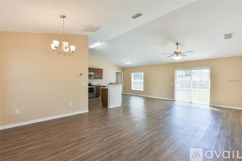 A spacious living room with wooden floors and a ceiling fan.
