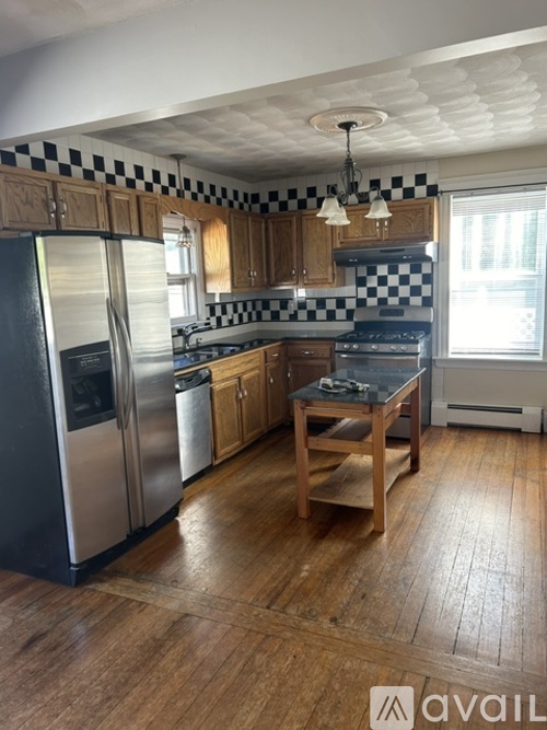 A kitchen with wooden floors and black and white checkered backsplash.