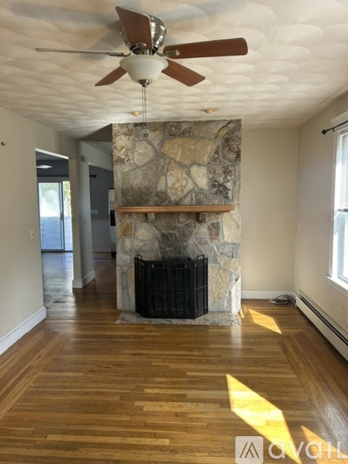 A room with a stone fireplace and wood flooring.