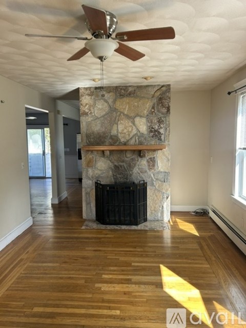 A room with a stone fireplace and wood flooring.