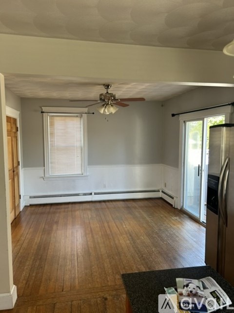 A living room with a ceiling fan and wooden floors.
