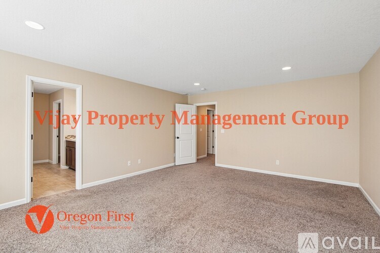 A spacious room with carpeted floor and white walls, with text overlays indicating it is managed by V????? Property Management Group and Oregon First.