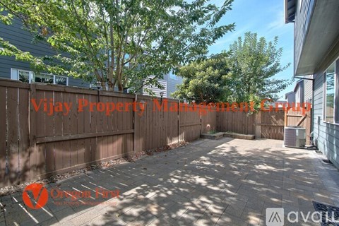 A sunny backyard with a wooden fence and trees.