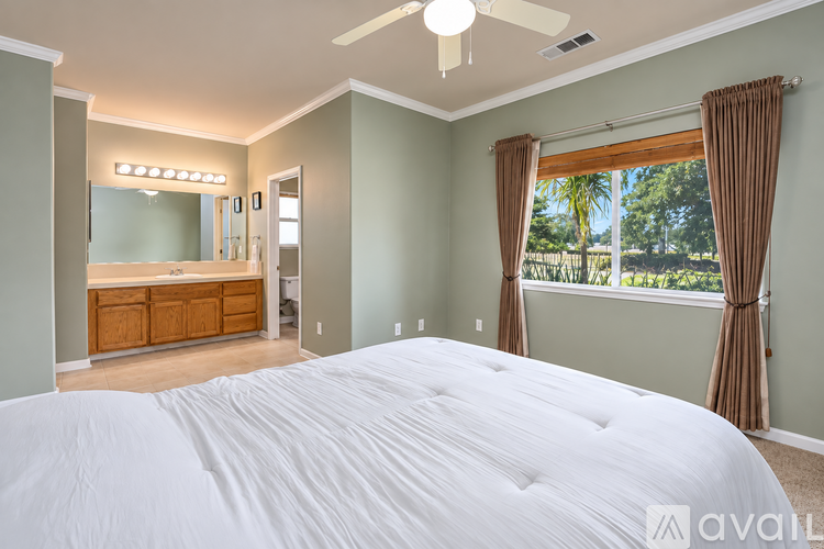 A bedroom with a large bed and a vanity with lights.