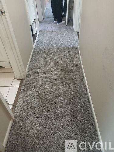 A hallway with a carpeted floor and a person standing at the end.