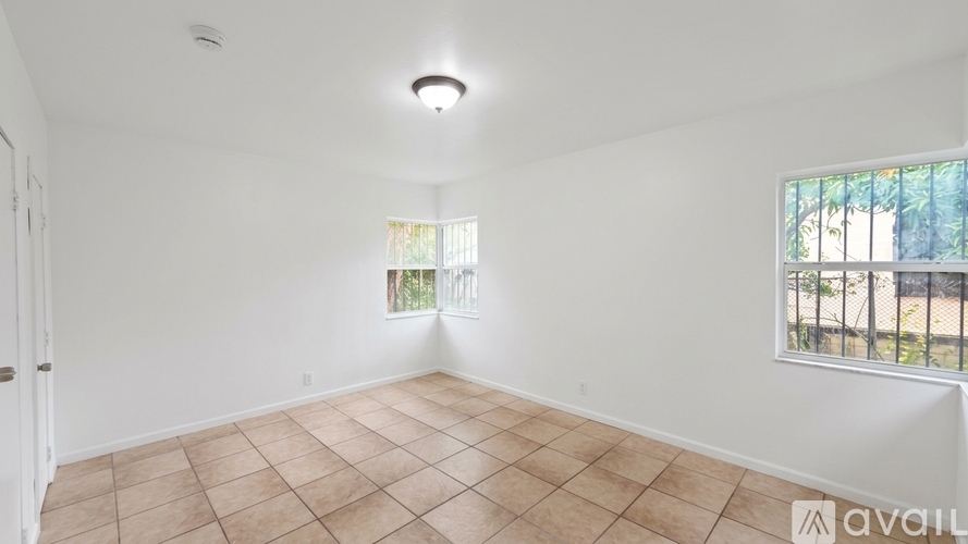 A room with a tiled floor and a window with a view of a fence and trees.