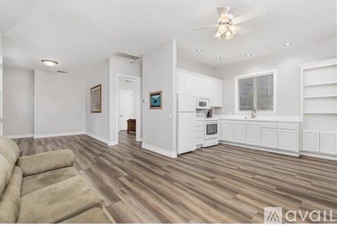 A spacious living room with a couch and a kitchen area in the background.