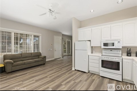 A kitchen with white appliances and a brown couch.