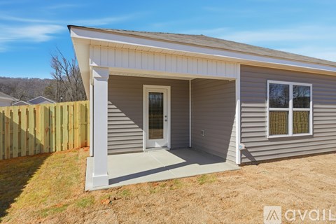 A small house with a porch and a fence in front.