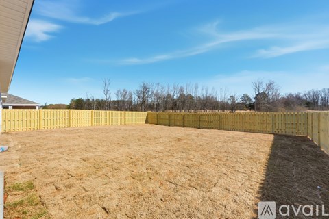 A backyard with a wooden fence and a clear blue sky.