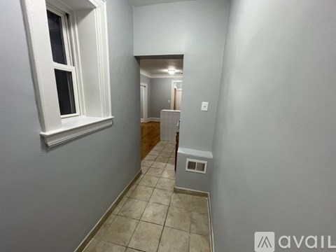 A hallway with tiled floors and white walls.