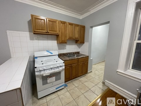 A kitchen with a white stove top oven and wooden cabinets.