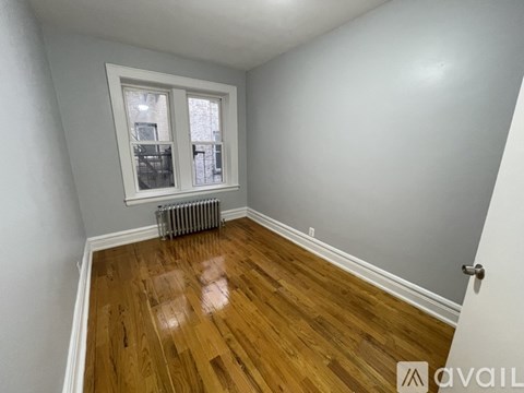 A room with wooden flooring and a window with a view of a building outside.