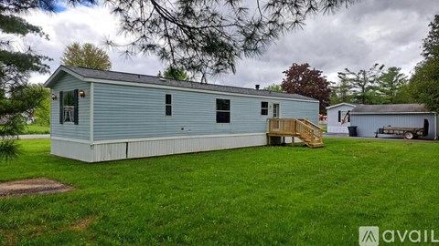A blue house with a white roof and a wooden deck.