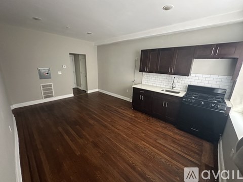 A kitchen with dark wood floors and white walls.