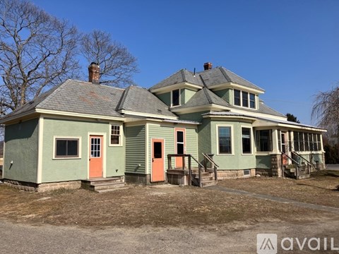 A green house with a red door is for sale.
