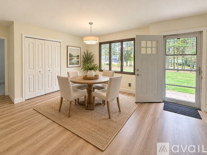 A dining room with a table set for four and a view of the backyard through the sliding glass doors.