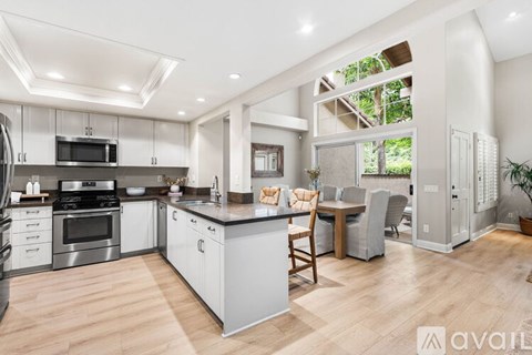 A modern kitchen with wooden floors and stainless steel appliances.