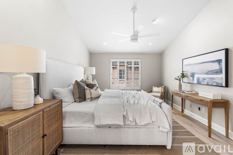 A bedroom with a bed, nightstand, and a ceiling fan.