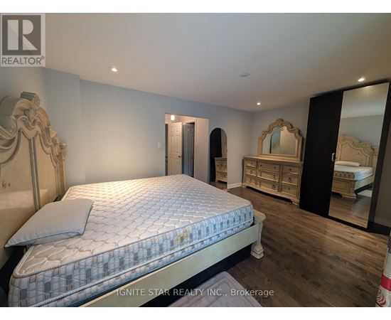 A bedroom with a large bed and a dresser with a mirror.