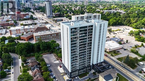 A tall building stands in the middle of a city with roads and other buildings in the background.