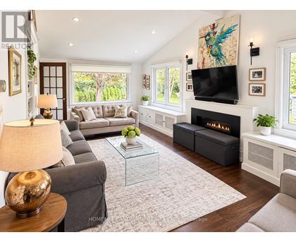 A living room with a grey couch, a glass coffee table, a fireplace, and a painting on the wall.