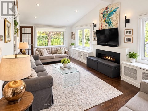 A living room with a grey couch, a glass coffee table, a fireplace, and a painting on the wall.
