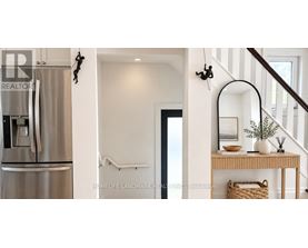 A stainless steel refrigerator is in a kitchen next to a staircase.