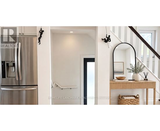 A stainless steel refrigerator is in a kitchen next to a staircase.