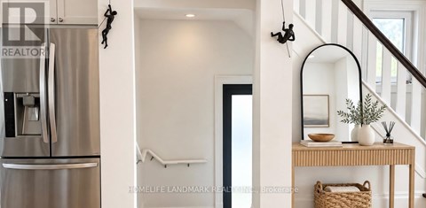 A stainless steel refrigerator is in a kitchen next to a staircase.